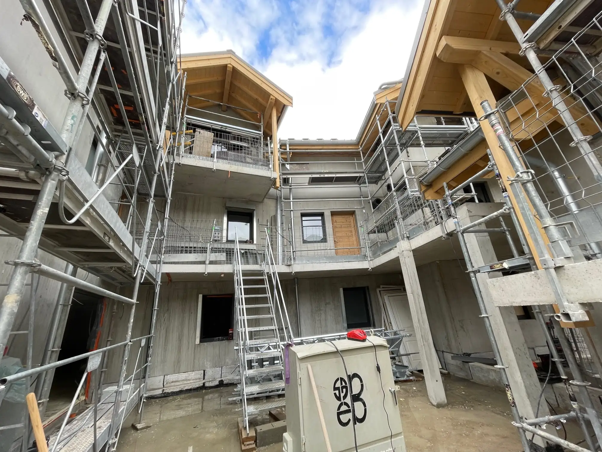 Cour d’un chantier de chalets sous échafaudage, charpente bois en place