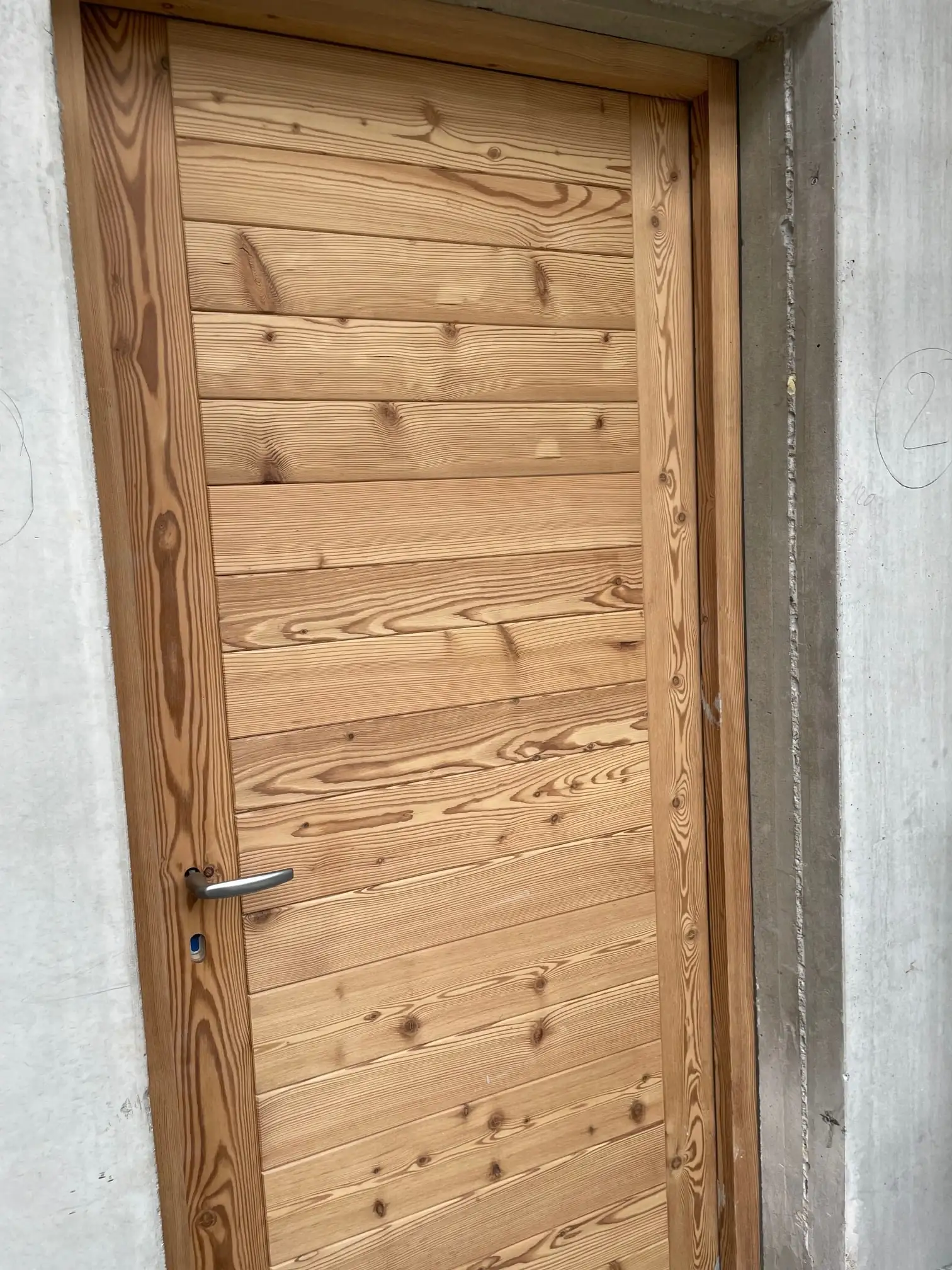 Porte en lames de bois posée dans une ouverture en béton